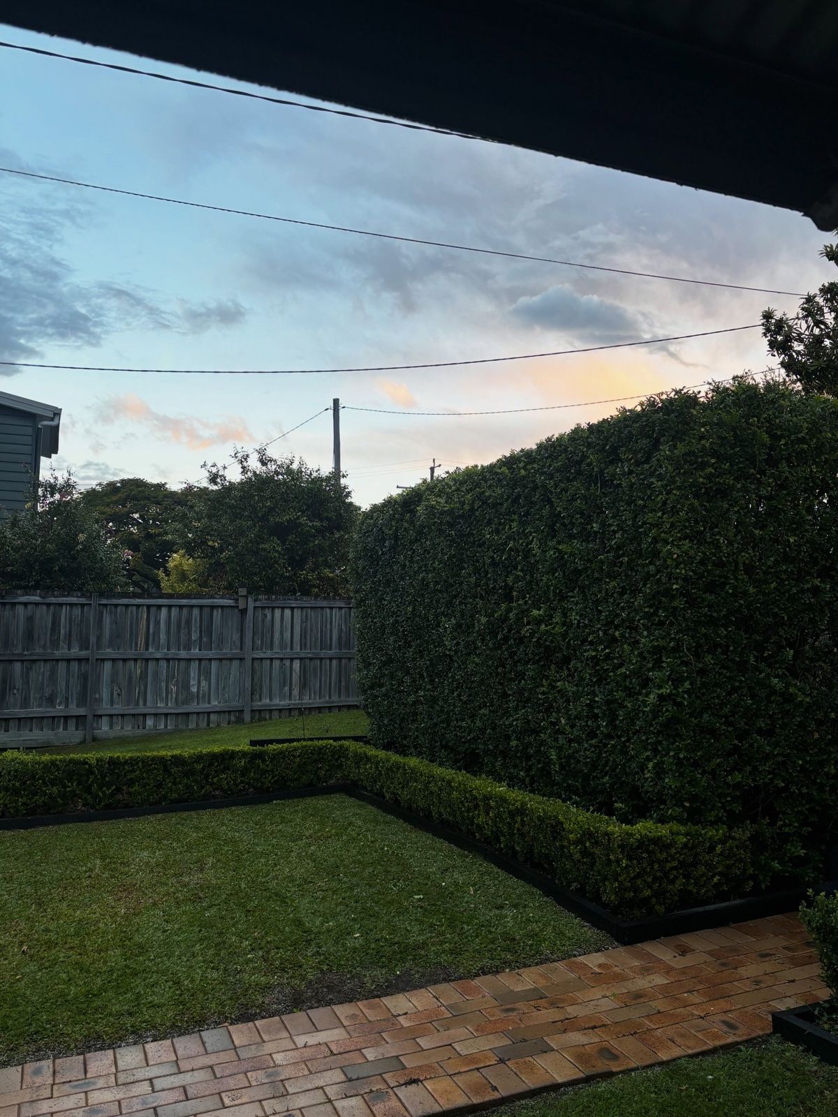 Neatly edged lawn and square-trimmed hedges beside a brick path