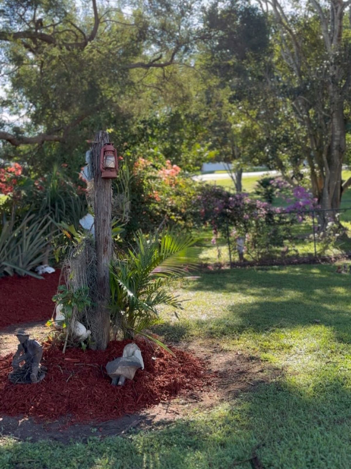 Garden bed finished with fresh red mulch around a tree stump feature