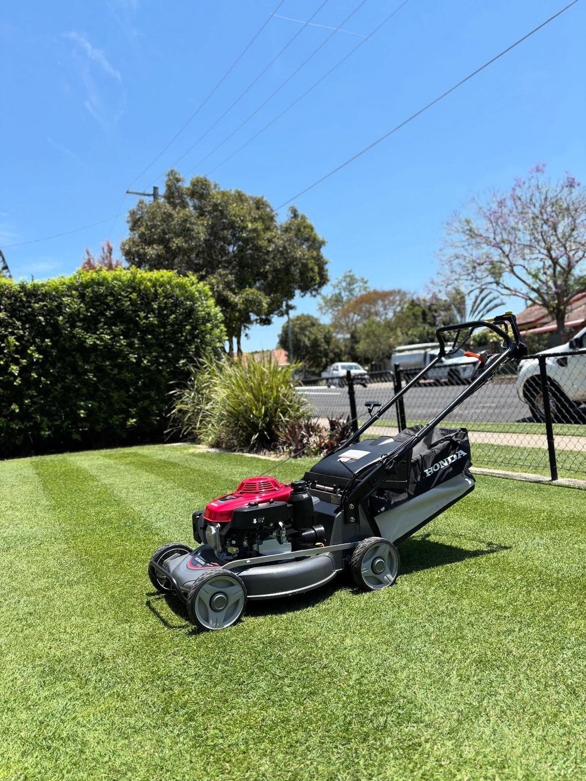 Honda mower parked on a freshly striped lawn on a sunny Brisbane day